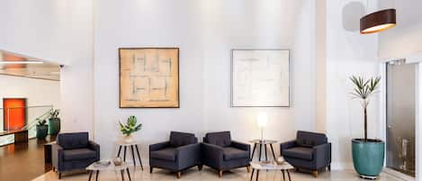 En moderne lobby med siddeområde, to store abstrakte malerier og en potteplante.