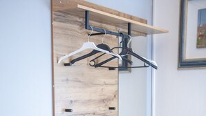 Ein Zimmer mit integriertem Kleiderschrank, einem schwarzen Schrank und einer Wandpaneele aus Holz.