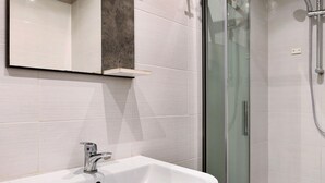 Ein Badezimmer mit Waschbecken, Spiegel und Duschkabine.