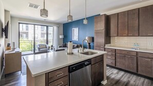 Et moderne køkken med en central ø, rustfrie hvidevarer og udsigt til en balkon.