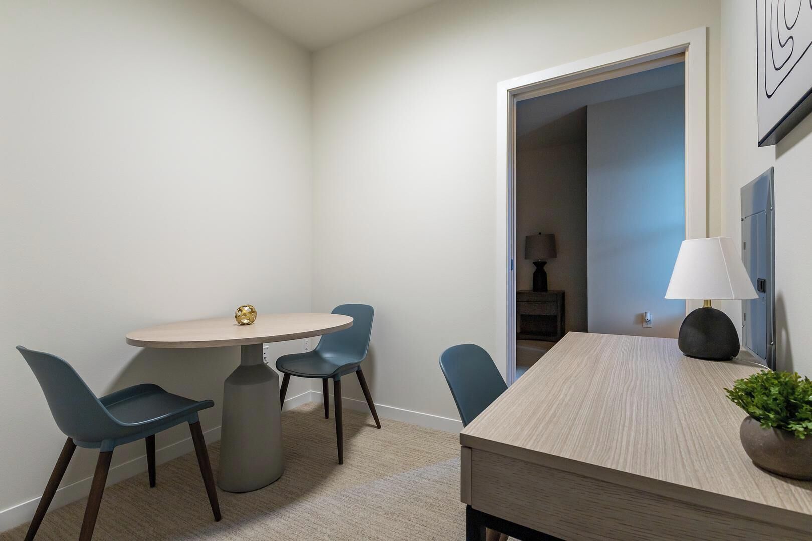 A modern room with a round table, two chairs, a lamp, and a potted plant.