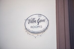 Ein rundes Schild mit dem Text 'Villa Giove ROOMS' und einer Website-Adresse.