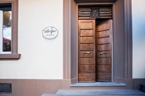 A double wooden door with a metal handle, a small window with a brown frame, and a sign on the wall reading 'Villa Gove ROOMS'. - Papavero Room – Double with Wi-Fi, A/C, and Accessible Bathroom (Prato)