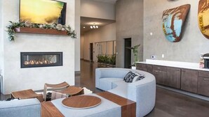Een modern interieur met een gebogen zithoek, een open haard en kunst aan de muren.