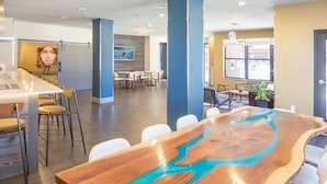 Een moderne vergaderruimte met een bijzondere houten tafel, afgewerkt met een blauw rivierdesign, witte stoelen en een helder interieur met natuurlijk licht.