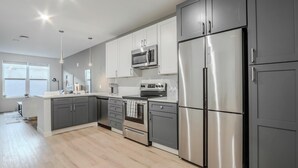 Une cuisine moderne avec des meubles gris, des appareils en acier inoxydable et un îlot central.