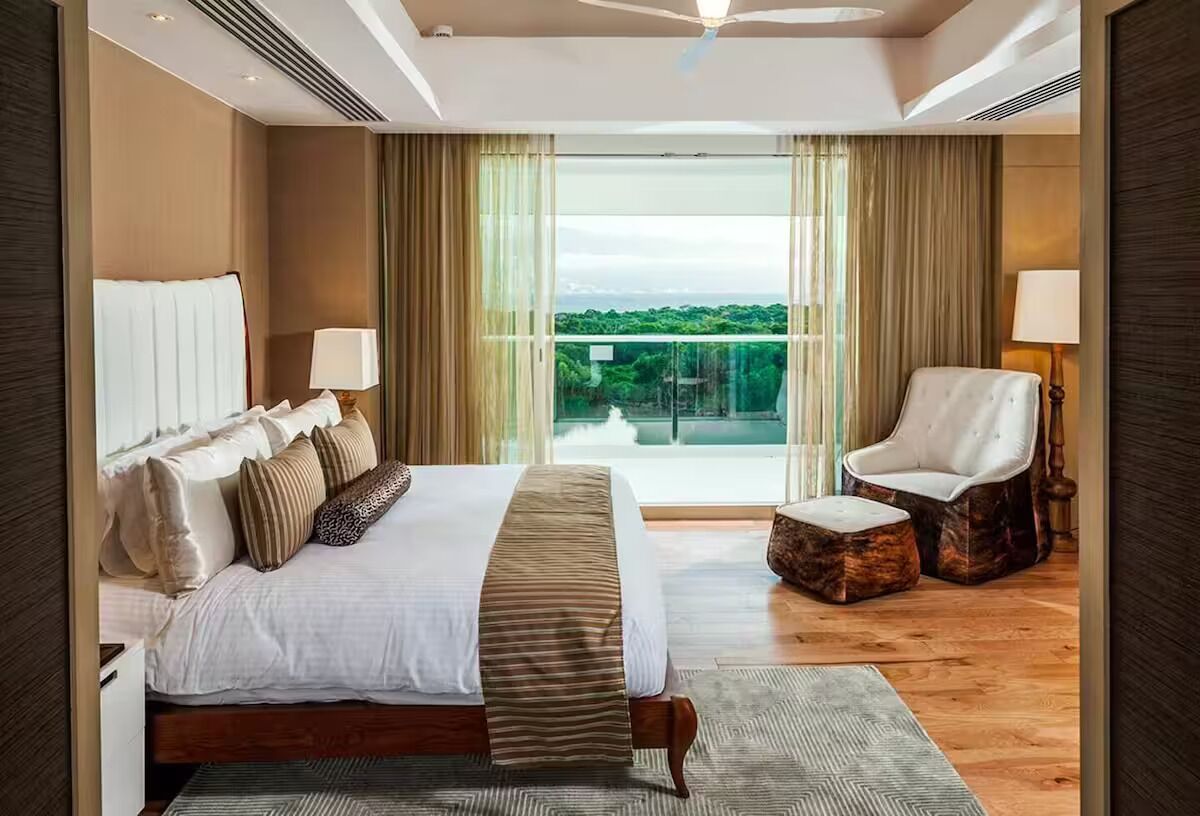 Una moderna camera d'hotel con un letto grande, un'area relax con una poltrona e vista sull'esterno.