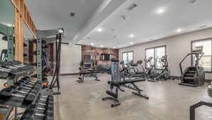 Ett gym med olika typer av träningsutrustning, inklusive löpband, crosstrainers och fria vikter.