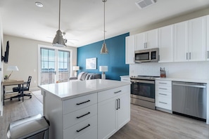 A modern kitchen with white cabinets, a stainless steel microwave, and an oven. - Landing | Modern 1BD, Game Room, Yoga Studio (Savannah)
