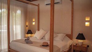 A four-poster bed with a quilted duvet, two bedside lamps, and a nightstand with a lamp. - Ph 10mins from tulum beach, with private pool and spa, ideal for families. (Tulum)