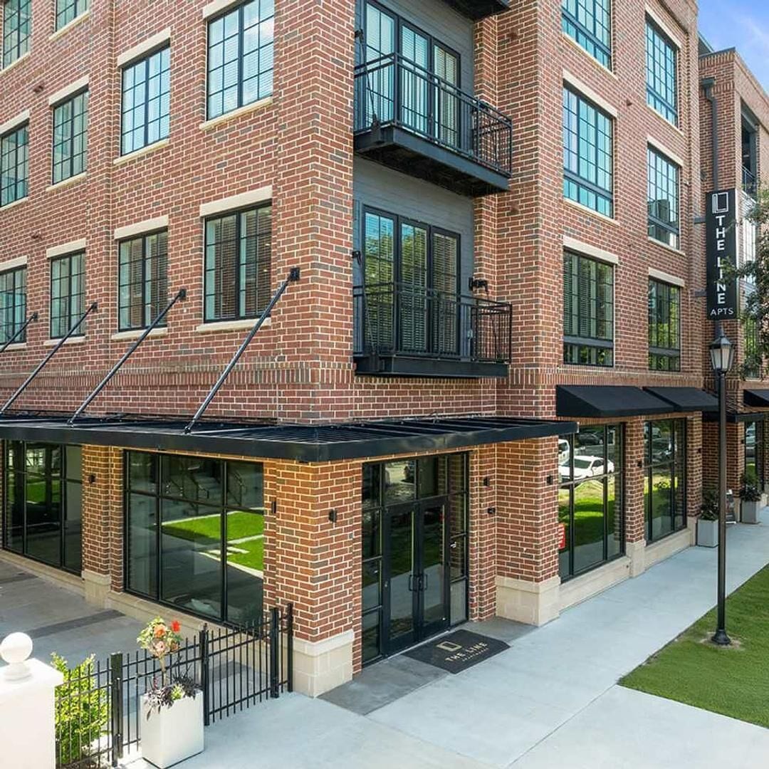 A multi-story brick building with large windows and a covered entrance area.