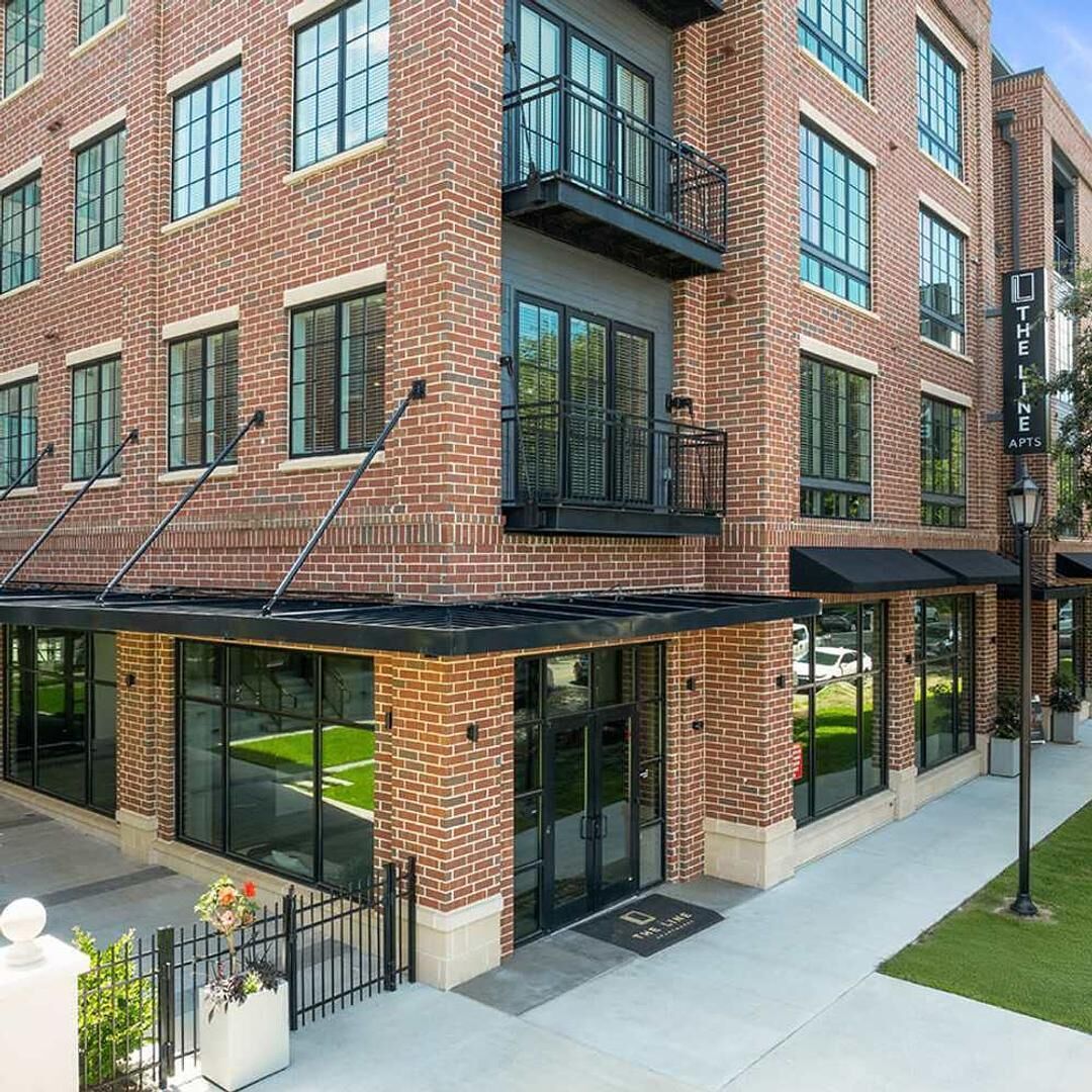 A multi-story brick building with large windows and a covered entrance area.