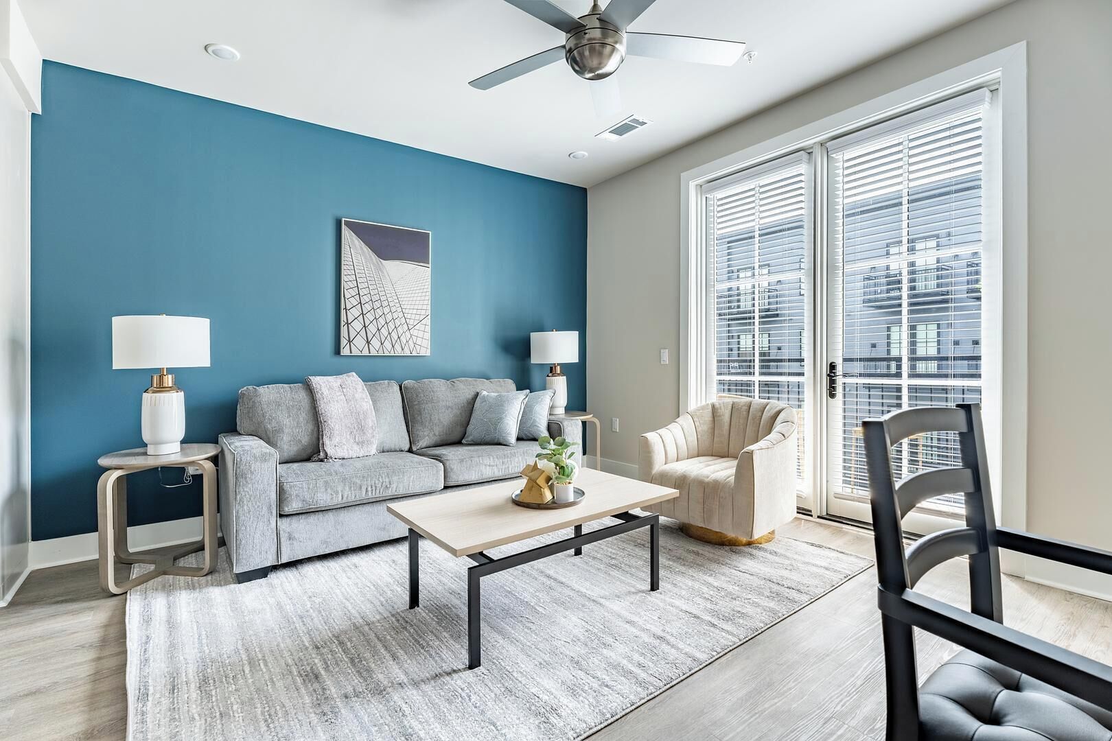 Ein modernes Wohnzimmer mit blauer Akzentwand, einem grauen Sofa, einem Couchtisch und einem Sessel.