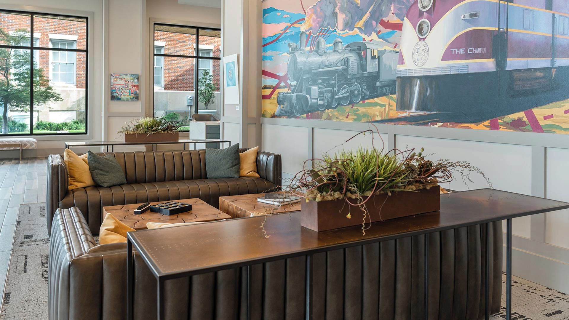 Et moderne loungeområde med sofa, sofabord og en dekorativ plante i midten.
