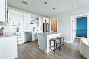 A modern kitchen with white cabinetry, a central island, and bar stools.