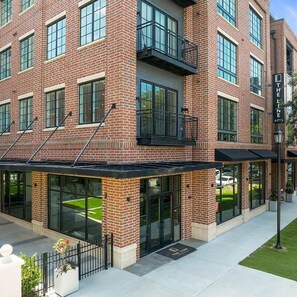 A multi-story brick building with large windows and a covered entrance area.