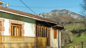 A traditional building with a balcony, stone walls, and a mountain backdrop. - Apartment 'Casa Geli 2' in La Robellada, Onís – Up to 9 Guests, 4 Bedrooms, 2 Bathrooms (La Robellada)