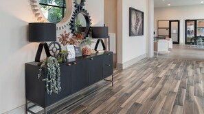 A modern interior with a black console table, decorative items, and a herringbone wood floor. - Landing | Modern 2BD, Game Room, Gym (Savannah)