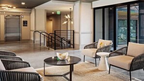 A modern lobby with a reception desk, seating area, and a staircase. - Landing | Spectacular 2BD, Game Room, Pool (Savannah)