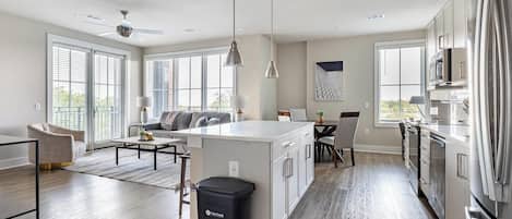 A modern kitchen with a central island, large windows, and a dining area.