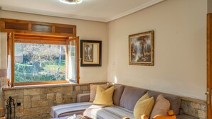 Une pièce chaleureuse avec un mur en pierre, un banc en bois, un canapé confortable et une table agrémentée d’un objet décoratif.
