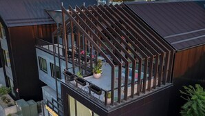 Un bâtiment moderne doté d’une terrasse sur le toit, agrémentée d’une structure de pergola en bois.