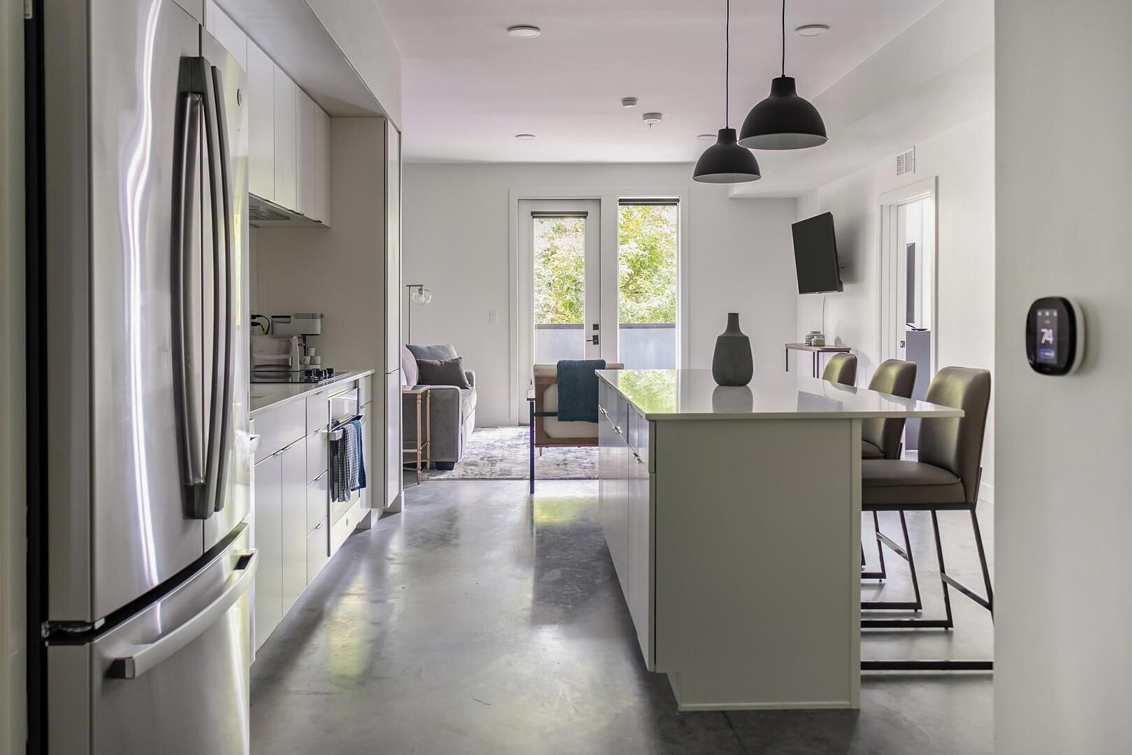 Uma cozinha moderna com ilha central, eletrodomésticos de aço inoxidável e área de refeições com mesa e cadeiras.