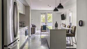 Une cuisine moderne dotée d’un îlot central, d’appareils électroménagers en acier inoxydable et d’un coin repas avec une table et des chaises.