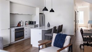 Eine moderne Küche mit weißen Schränken, einer zentralen Kochinsel und einem Essbereich mit Tisch und Stühlen.