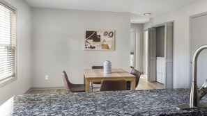 A modern kitchen with a granite countertop, a stainless steel faucet, and a dining area with a wooden table and chairs. - Landing | Beautiful 2BD, Clubhouse, Pool (Raleigh)