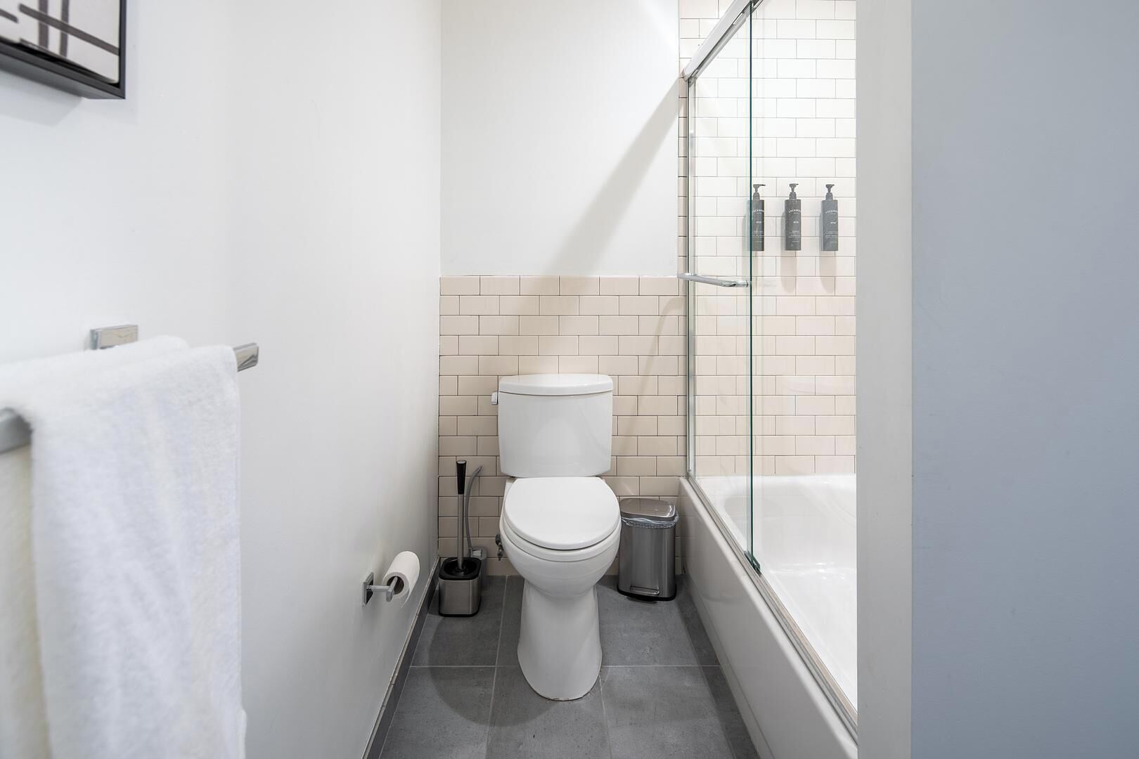 A modern bathroom with a toilet, a glass shower enclosure, and a bathtub.