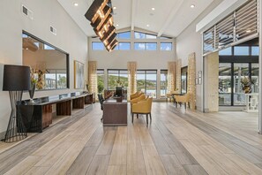 A spacious, modern hotel lobby with a long reception desk, comfortable seating, and large windows offering views of the outdoors. - Landing | Incredible 2BD, Gym, Yoga Studio (San Antonio)