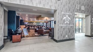En modern lobby med en receptionsdisk, en sittgrupp och en skylt som välkomnar gästerna till Grande Cayman Resort.