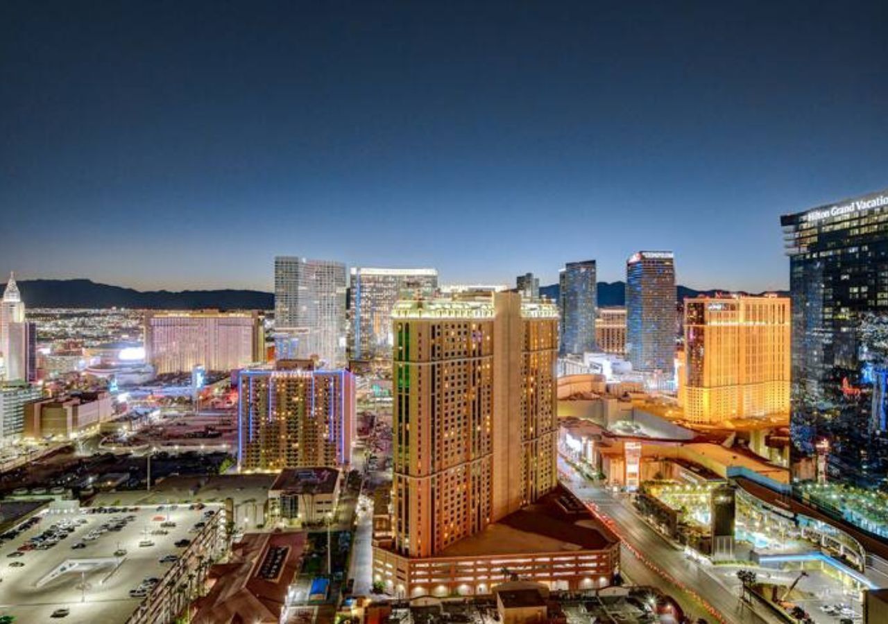 A cityscape at night with illuminated buildings, including a prominent hotel with a sign.