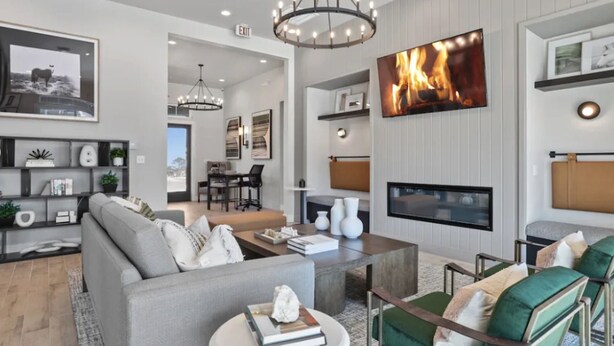 A modern living room with a fireplace, a large TV, and a dining area with a view.