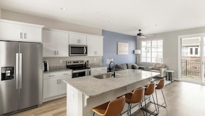 A modern kitchen with stainless steel appliances, a granite countertop, and a bar area with stools.