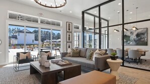 A spacious living room with a large sofa, coffee table, and a dining area with chairs and a table.