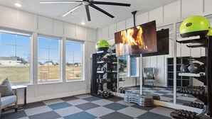 A home gym with a large TV, weight racks, and a view of the outdoors.