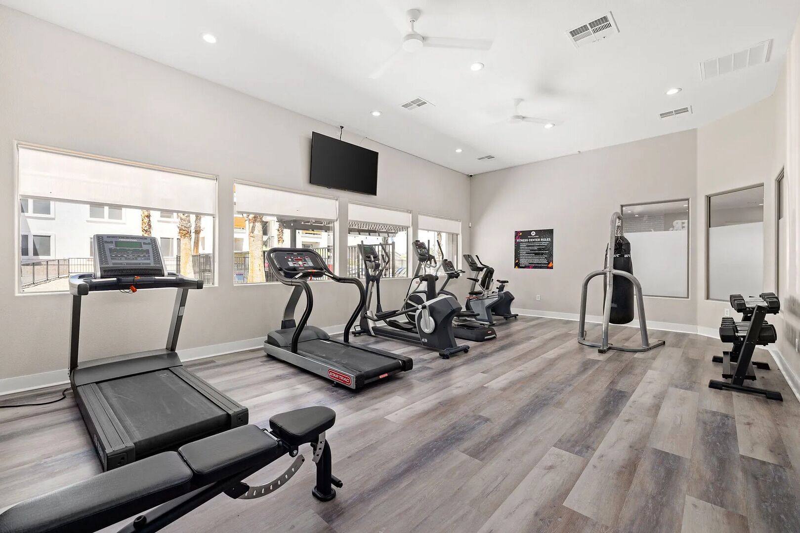 Une salle de sport équipée de tapis de course, de vélos elliptiques et de matériel de musculation.