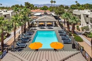 A rooftop pool with lounge chairs and umbrellas, surrounded by palm trees and a view of mountains. - Landing | Stylish 1BD, Gym (Las Vegas)