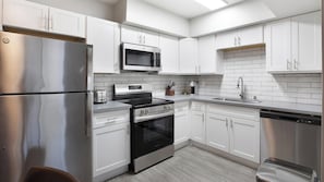 A modern kitchen with stainless steel appliances, white cabinetry, and a tiled backsplash. - Landing | Chic 1BD, Gym (Las Vegas)