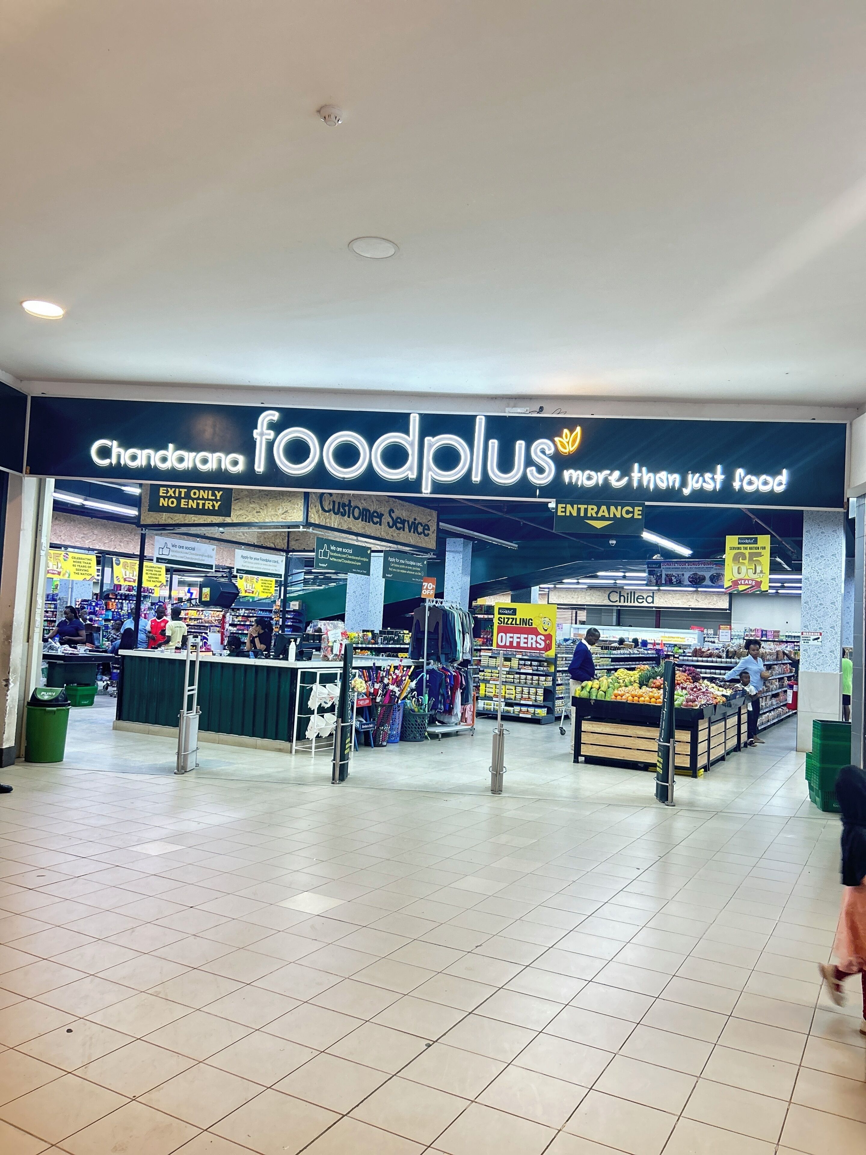 Un mercado de alimentos con un letrero que dice 'Chandarana foodplus más que solo comida'.