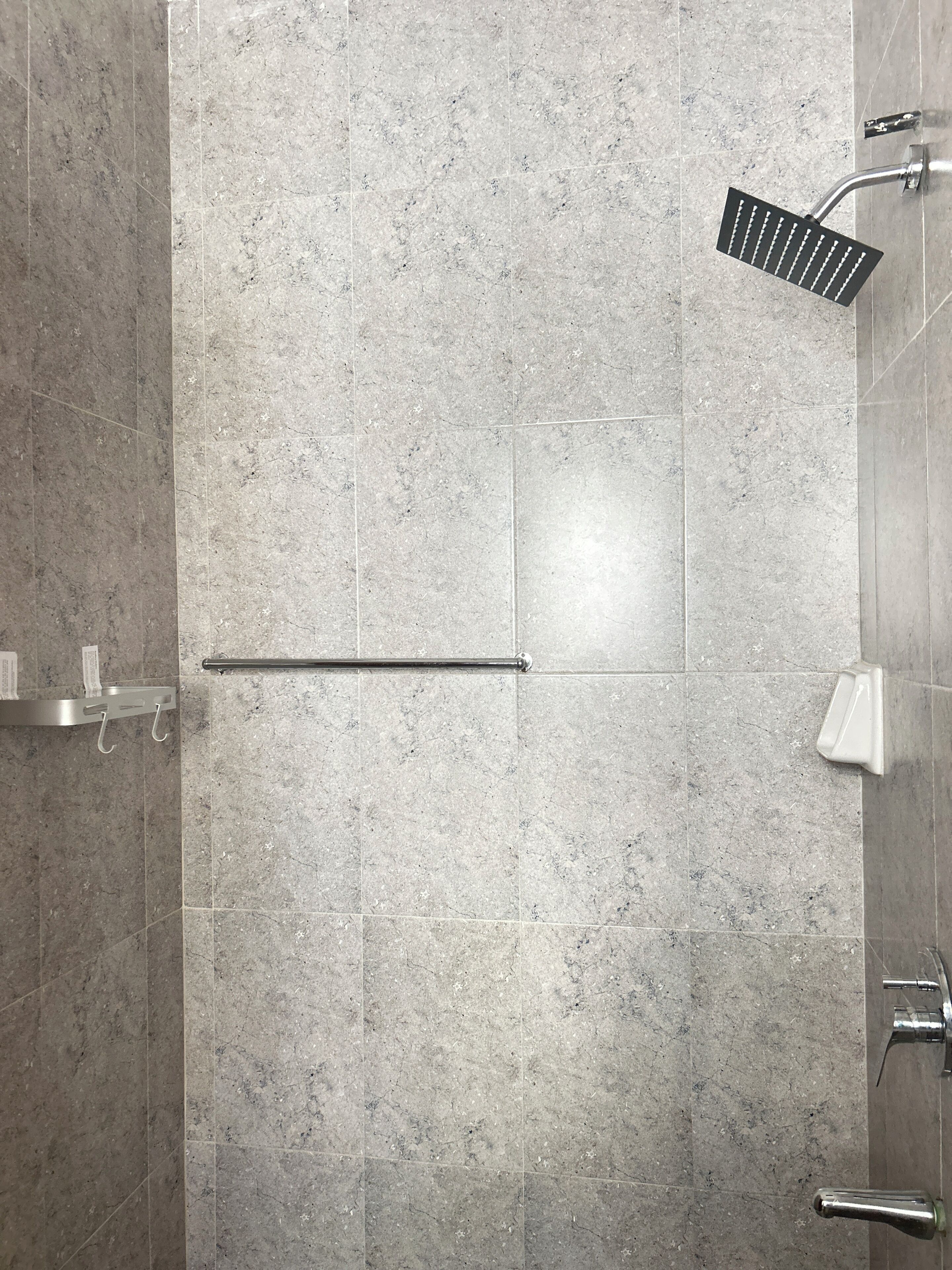 Un baño moderno con ducha, toallero y secamanos.