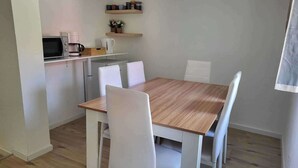 A small, modern kitchen with white appliances, a wooden dining table, and white chairs. - 3-bed Cosy Apartment - Sleeps 7 (Villingen-Schwenningen)