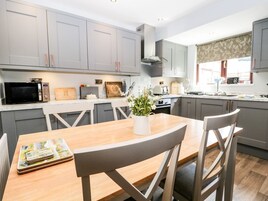 Una cocina moderna con armarios grises, una mesa de comedor de madera y un jarrón con flores.