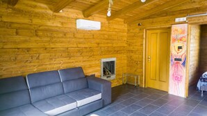 A log cabin interior with a gray sofa, a fireplace, and a wooden door.