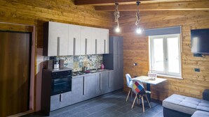 A compact kitchen with modern appliances, a dining area with a table and chairs, and a window providing natural light.