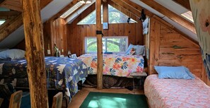 Une chambre mansardée chaleureuse avec des murs en bois, deux lits, une petite table et une fenêtre.