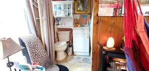 A compact bathroom with a toilet, a sink, and a cabinet. There is a leopard-print chair and a lamp near the window. - Magical Tree House Rental Nestled in the Woods on Farm Retreat near St. Louis, Missouri (Grubville)