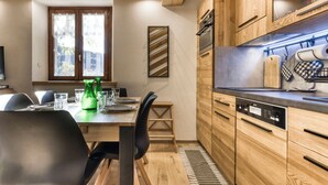 Eine moderne Küche mit Holzschränken, einem eingebauten Backofen und einem Essbereich mit Tisch für vier Personen.